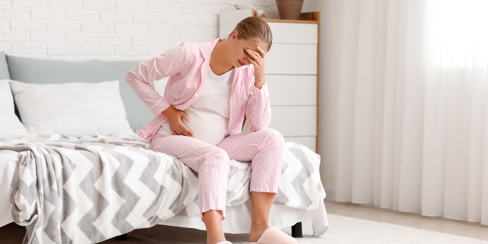 Donna incinta ansiosa sul suo divano, che simboleggia le sfide emotive e la necessità di supporto per gestire l'ansia durante la gravidanza