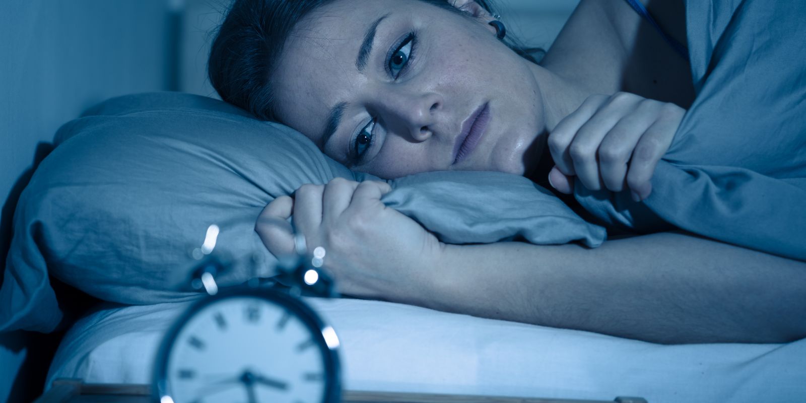 Mujer que se despierta sintiéndose mal, lo que ilustra los efectos de los trastornos del sueño y la búsqueda de soluciones para mejorar el bienestar