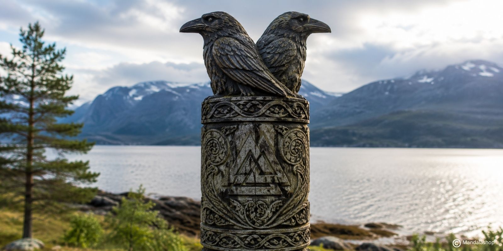 Due corvi, Huginn e Muninn, scolpiti su una stele decorata con un Valknut di fronte a un fiordo